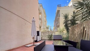 Une terrasse avec des meubles d’extérieur, une table et un buffet blanc.