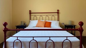 Una cama bien hecha con cabecera de madera, dos mesitas de noche y una lámpara a cada lado.