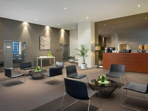 Relax in our inviting lobby, featuring a reception desk, comfortable seating area, and a touch of greenery.