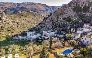 A mountainous village with white buildings, a swimming pool, and a clear view of the surrounding landscape.