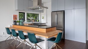Une cuisine moderne dotée d’un îlot central, d’appareils électroménagers en acier inoxydable et de chaises de couleur turquoise.