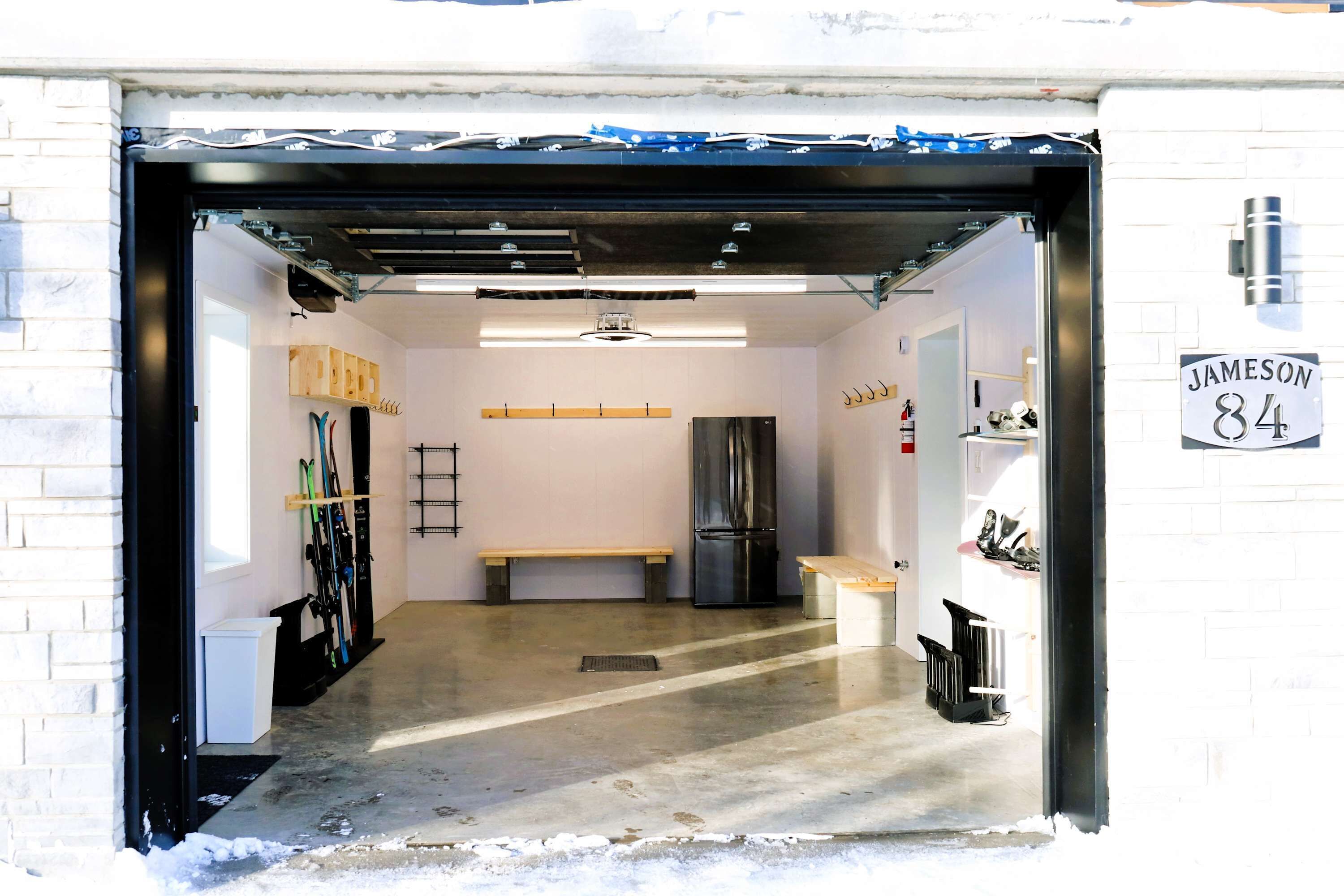 Un garage avec un établi, un réfrigérateur et une pancarte sur laquelle on peut lire « Jameson 84 ».