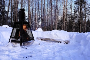A metal fire pit in a snowy forest.