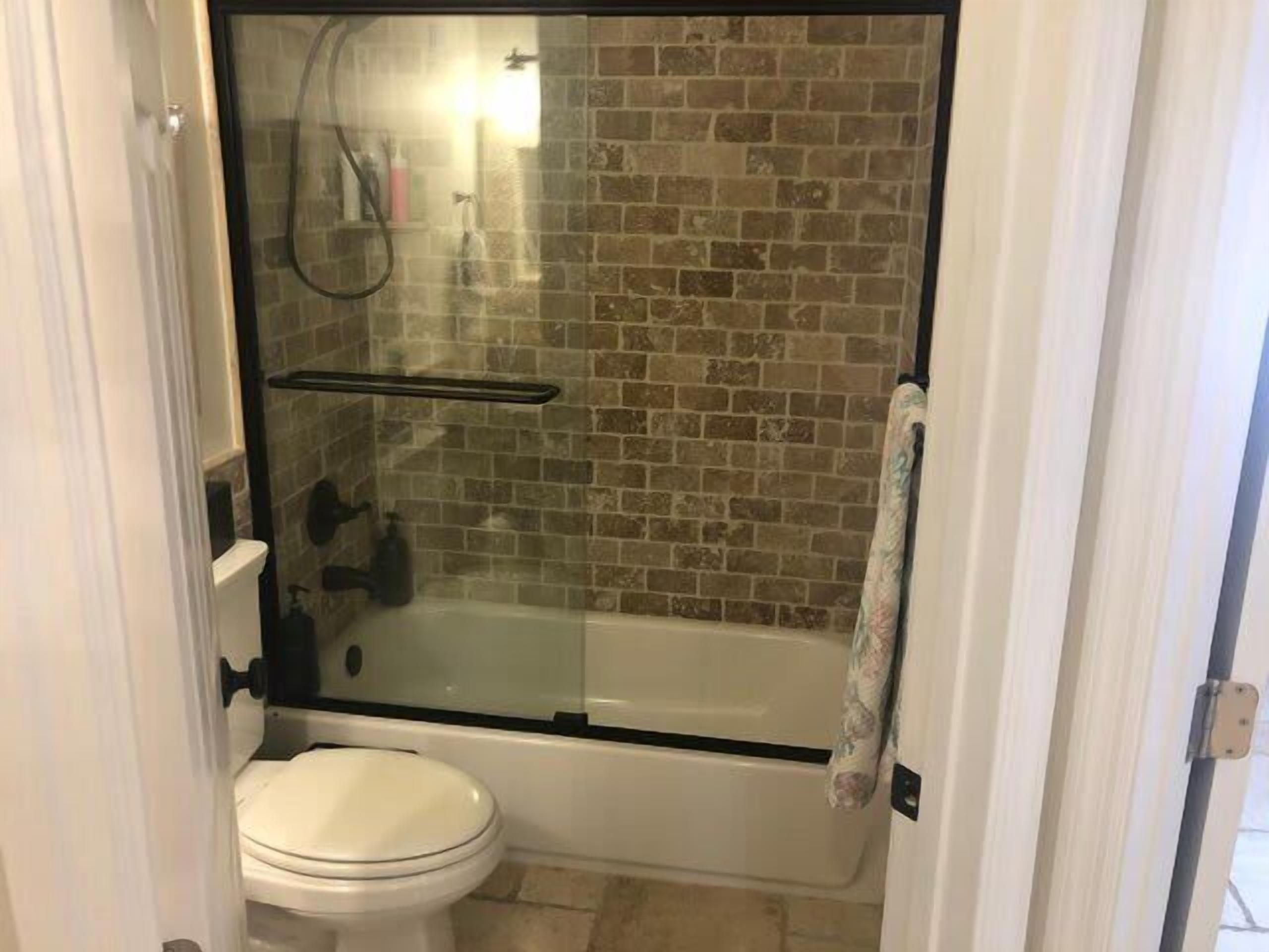 A bathroom with a glass-enclosed shower, a white toilet, and a bathtub.