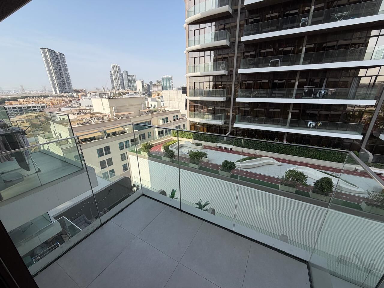 A modern building with multiple balconies, a glass facade, and a view of a cityscape with other high-rise buildings.