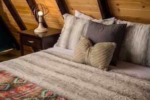A bed with a striped blanket, a patterned throw, and striped pillows. - Charming Rocky Mountain A-Frame (Fraser)