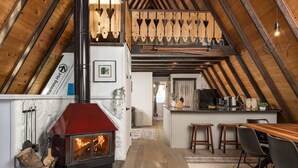 A loft-style room with a wood-burning stove, a kitchen area, and a dining space.