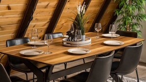 A dining table set with plates, glasses, and a centerpiece in a room with wooden walls and a plant.