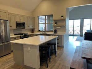A modern kitchen with a central island, stainless steel appliances, and a large window providing natural light.