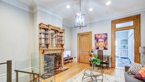 A spacious living room with a fireplace, a glass railing, a sofa, and a dining area. - Logan Mansion Suite 2 2 Bedroom Apartment Hotel (Washington)