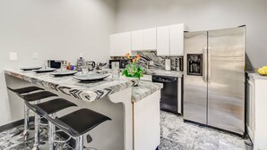 A modern kitchen with a marble countertop, stainless steel appliances, and bar stools. - Logan Mansion Suite 2 2 Bedroom Apartment Hotel (Washington)