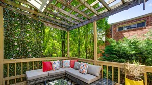 A covered patio with a wooden bench, a glass-top table, and a potted plant. - Logan Mansion Suite 2 2 Bedroom Apartment Hotel (Washington)