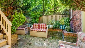 A patio with a wooden bench, a cushioned sofa, and a striped chair. - Logan Mansion Suite 4 2 Bedroom Apartment Hotel (Washington)