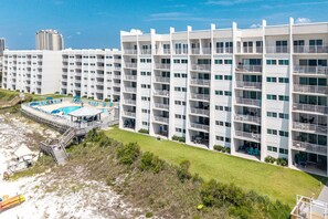 A multi-story hotel with balconies, a swimming pool, and a beach area. - Beach House 501a 2 Bedroom Condo (Miramar Beach)