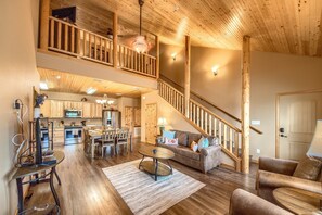 A spacious living area with a wooden staircase, a dining area, and a kitchen.