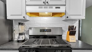 A kitchen with a stove, a blender, and a knife block. - Charming Pastel Duplex in the Heart of Tulsa (Tulsa)