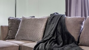 A sofa with multiple cushions and a blanket. - Charming Pastel Duplex in the Heart of Tulsa (Tulsa)