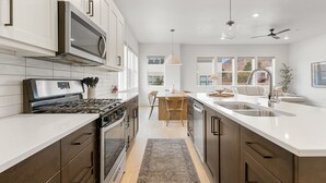 Een moderne keuken met witte kasten, roestvrijstalen apparatuur en een groot keukenblok met een spoelbak.