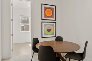 A conference room with a round wooden table, four black chairs, and two framed abstract paintings on the wall. - Villa #26 At Bloomington Country Club - Sunset Retreat 4 Bedroom Townhouse (St. George)