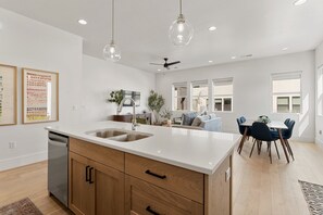 A modern kitchen with a central island, wooden cabinets, and pendant lighting. - Villa #26 At Bloomington Country Club - Sunset Retreat 4 Bedroom Townhouse (St. George)