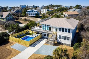 Une maison à deux étages avec une piscine, un patio couvert et un escalier menant à une terrasse.