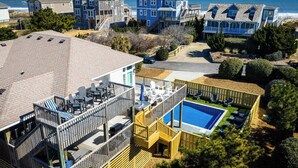 A residential area with a large house featuring a deck and a swimming pool. - Newly Renovated! Semi Oceanfront w/ Pool & Hot Tub (Duck)