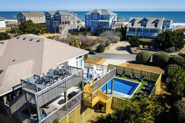 Un quartier résidentiel avec une grande maison dotée d’une terrasse et d’une piscine.