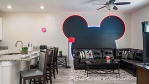 Ein modernes Wohnzimmer mit einer großen Couch, einem Couchtisch und einer Küchenzeile mit Bar.