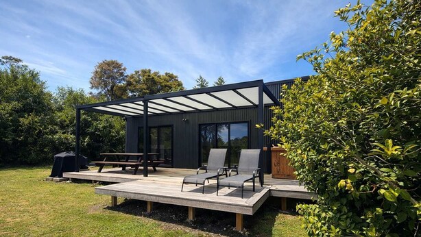 Eine moderne Außenterrasse mit Pergola, Sitzgruppe und Grill.