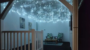 Una escalera con barandilla de madera que lleva a una habitación decorada con luces de cadena.