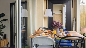 A breakfast table set with croissants, a bowl of fruit, and a glass of orange juice. - Charming with Garden | Near train station (Rennes)