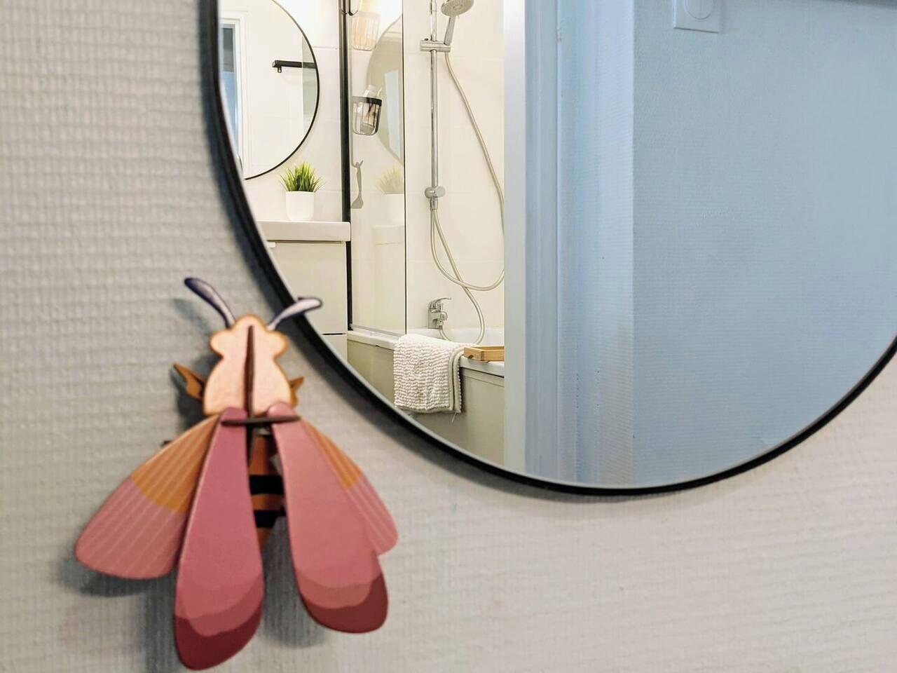 Une salle de bain avec un miroir rond, un porte-serviettes et une douche.