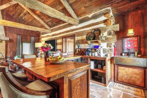 A rustic interior with a wooden bar, seating area, and stone flooring. - Luxury Hill Country Escape • Pool, Hot Tub, Firepit • Near Wineries (Wimberley)