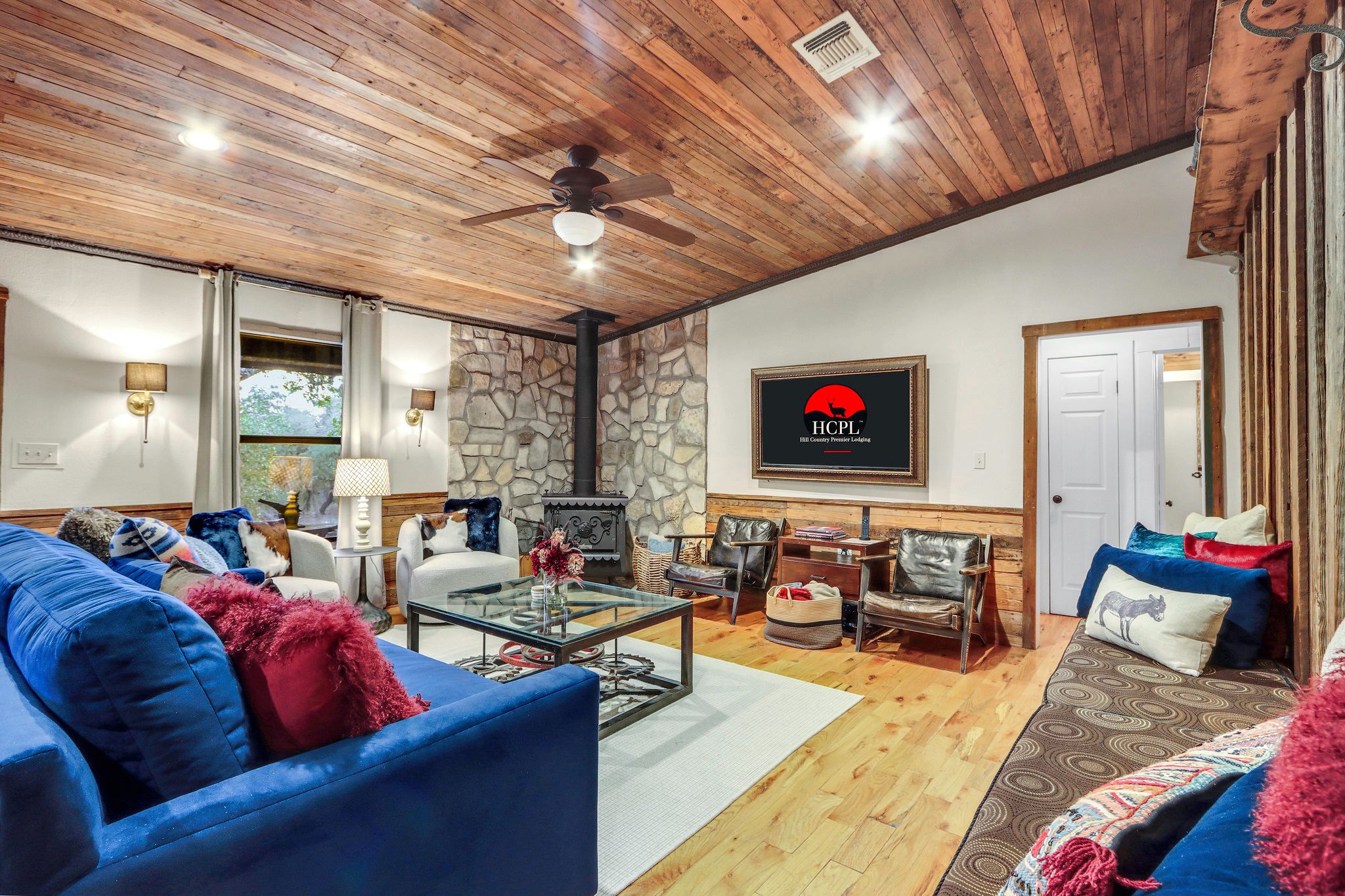 A cozy living room with a stone fireplace, comfortable seating, and a mounted television.