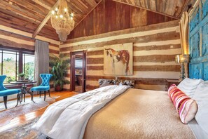 Camera da letto in stile baita con un ampio letto, un lampadario e un quadro di un toro.