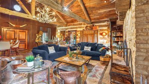 Un'atmosfera rustica con travi a vista in legno, un lampadario e un angolo salotto accogliente con divani e tavolino.