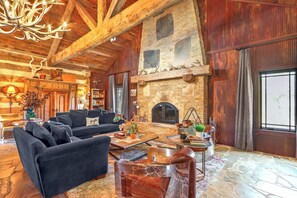 A rustic interior with a stone fireplace, wooden beams, and a black leather sofa. - Luxury Hill Country Escape • Pool, Hot Tub, Firepit • Near Wineries (Wimberley)