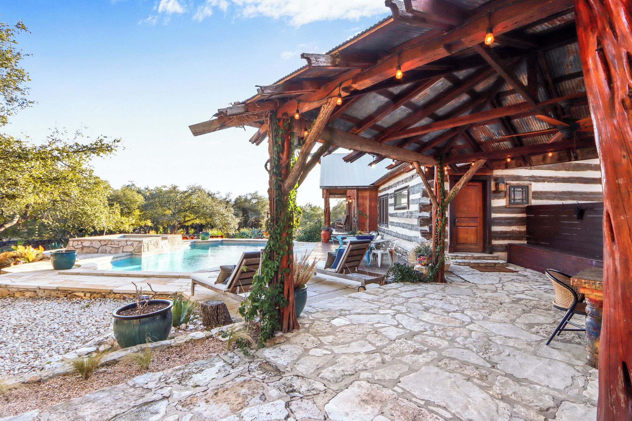 A rustic cabin with a stone patio, outdoor seating, and a swimming pool.
