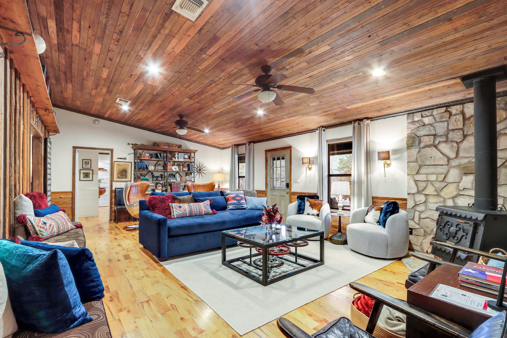 Un salon spacieux avec un plafond en bois, un mur en pierre et une cheminée.