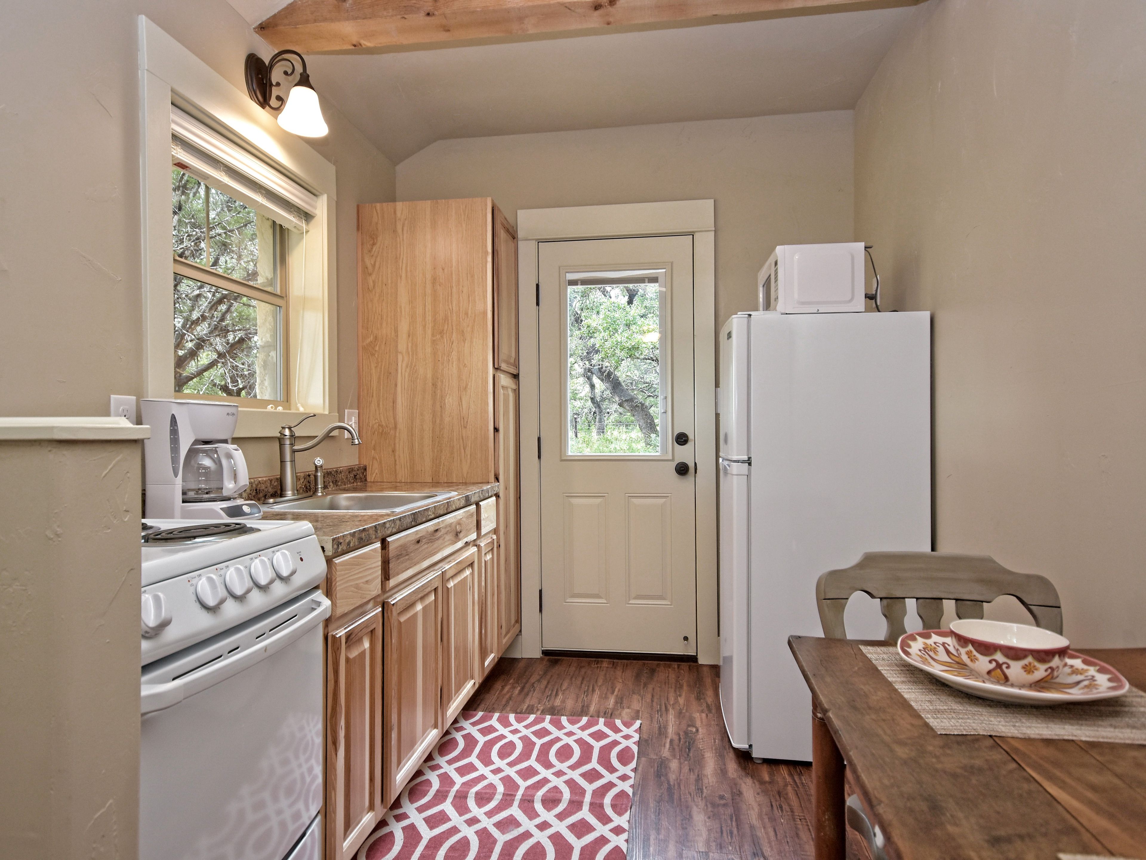 A compact kitchen with wooden cabinets, a white stove, a sink, and a refrigerator.