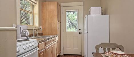 A compact kitchen with wooden cabinets, a white stove, a sink, and a refrigerator.