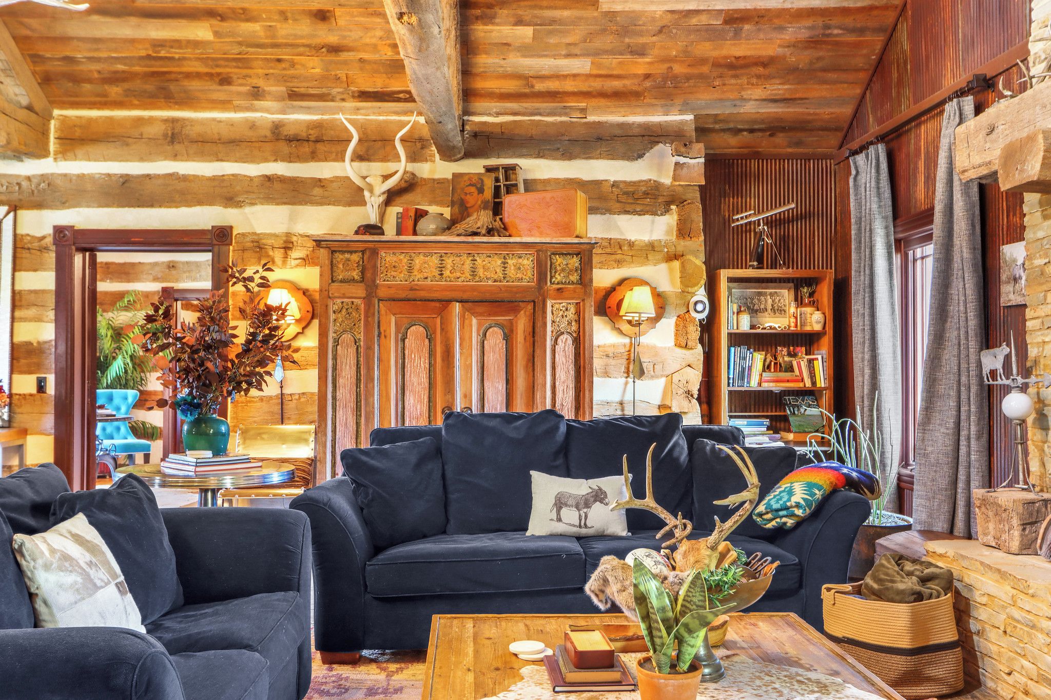 Una sala de estar acogedora con un sofá azul oscuro, una mesa de centro de madera y una estantería llena de libros y objetos decorativos.