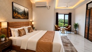 A modern hotel room with a large bed, a painting of a forest, an air conditioner, a ceiling fan, a dining area with chairs, and a view of greenery through the window. - Opal Villa by JMD Group (New Delhi)