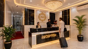 A hotel reception desk with a marble counter, a chandelier, and potted plants. - Opal Villa by JMD Group (New Delhi)