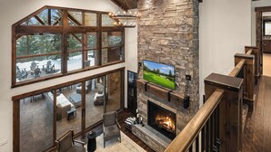 Un espacio habitable amplio con chimenea de piedra, ventanas grandes y un rincón de estar acogedor.