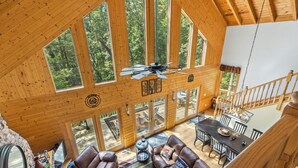A spacious wooden cabin with a large dining area, leather sofas, and a ceiling fan.