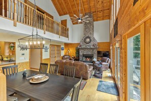 A spacious living area with a fireplace, leather seating, and a dining table. - Sweet Mountain Dreams - 2BR: Mountain Retreat w/ Lake Glenville Views, Firepit (Cullowhee)