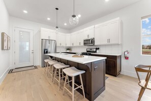 A modern kitchen with white cabinets, stainless steel appliances, and a central island with bar stools.