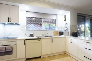 Una cocina moderna con armarios blancos, lavavajillas, microondas y fregadero.
