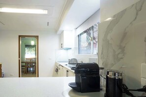 Une cuisine équipée d’une machine à café, d’une bouilloire et d’un four à micro-ondes, le tout posé sur le plan de travail.